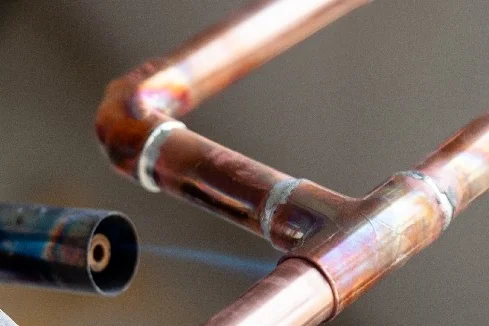 Kupferrohre werden mit einem Gasbrenner gelötet.